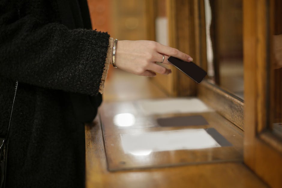 Close-up of a woman's hand using a black card for payment at an indoor counter.