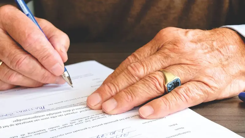 Person signing a housing complaint document at a desk